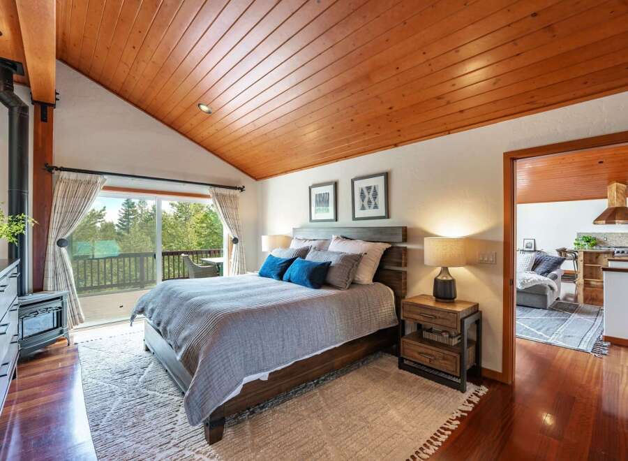 Experience cozy living in this charming bedroom featuring a rustic wood-paneled vaulted ceiling and a modern wood-burning stove.
