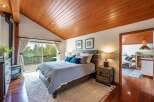 Experience cozy living in this charming bedroom featuring a rustic wood-paneled vaulted ceiling and a modern wood-burning stove.