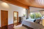 Experience serene living in this charming bedroom featuring a cozy wood-burning stove and a private balcony with breathtaking forest views.