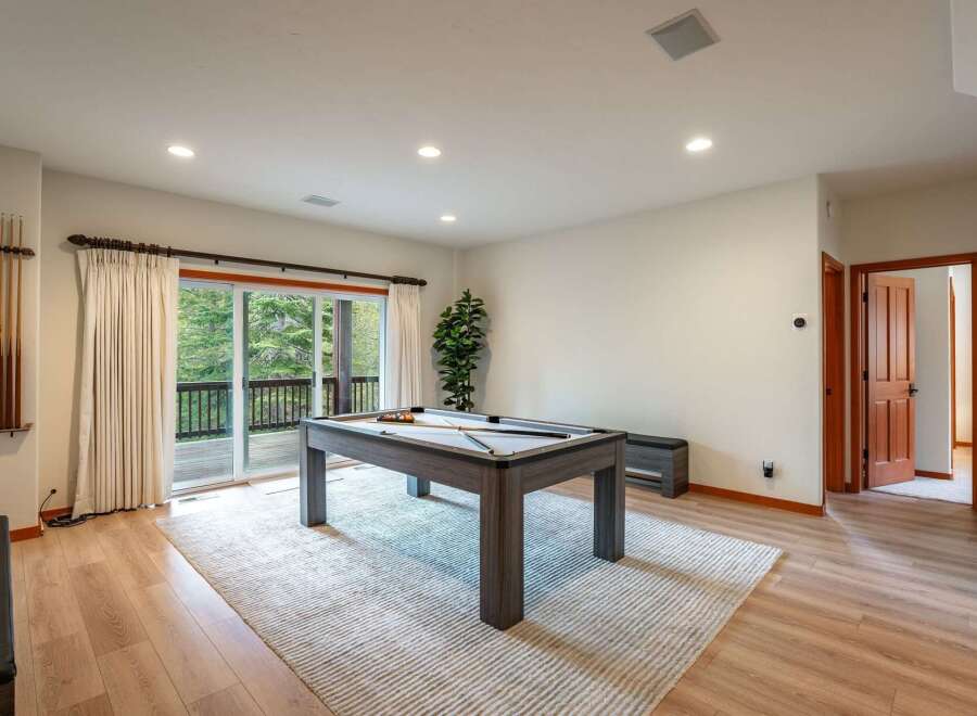 Enjoy endless entertainment in this spacious game room, featuring a modern pool table and ample natural light from the large sliding glass doors.