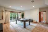 Enjoy endless entertainment in this spacious game room, featuring a modern pool table and ample natural light from the large sliding glass doors.