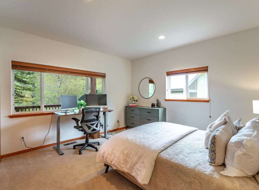 This inviting bedroom features a dedicated workspace with dual monitors, perfect for remote work or study.