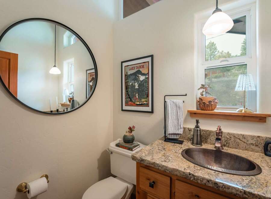 This charming bathroom features a large round mirror and a unique copper sink, adding a touch of rustic elegance.