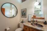 This charming bathroom features a large round mirror and a unique copper sink, adding a touch of rustic elegance.