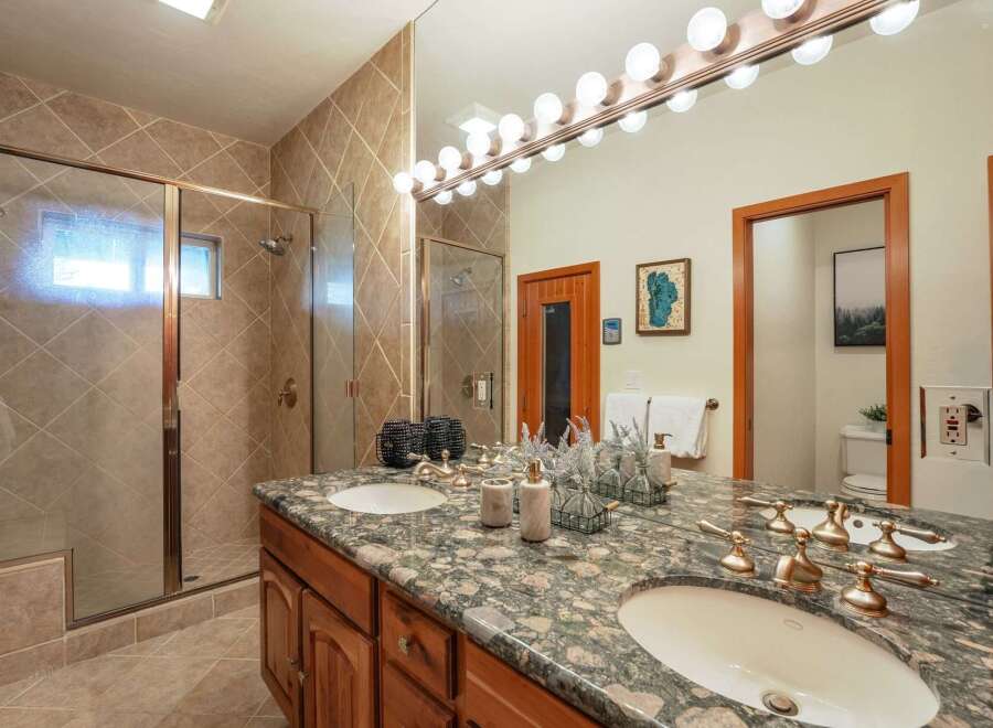 Experience luxury in this stunning bathroom featuring a spacious walk-in shower with elegant tile work and a dual vanity with a granite countertop.