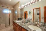 Experience luxury in this stunning bathroom featuring a spacious walk-in shower with elegant tile work and a dual vanity with a granite countertop.