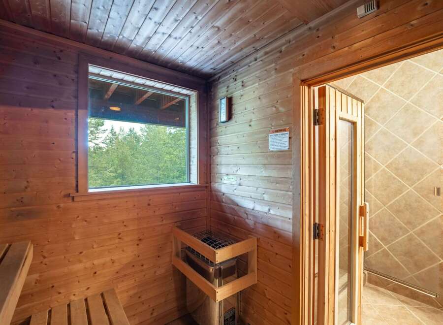 Experience ultimate relaxation in this luxurious sauna, featuring natural wood paneling and a large window with serene forest views.