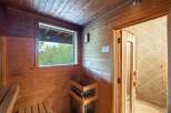 Experience ultimate relaxation in this luxurious sauna, featuring natural wood paneling and a large window with serene forest views.
