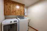 This laundry room features ample storage with beautiful knotty pine cabinets above the washer and dryer.