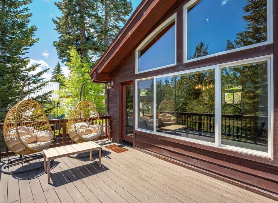 Enjoy the serene mountain views from this charming cabin's spacious deck, complete with comfortable hanging chairs and a coffee table.