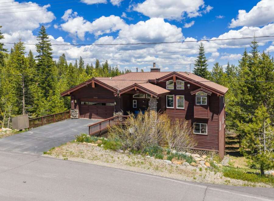 Nestled amidst a lush forest, this stunning mountain home offers a serene retreat with its rich wood siding and expansive windows.