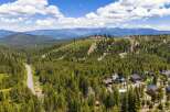 Discover your dream mountain retreat nestled amidst a lush pine forest, offering breathtaking panoramic views of snow-capped peaks and a serene lake.