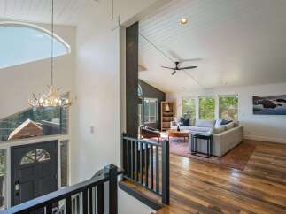 Experience breathtaking mountain views from this stunning home, featuring a grand entryway with a unique antler chandelier and a large, arched window.