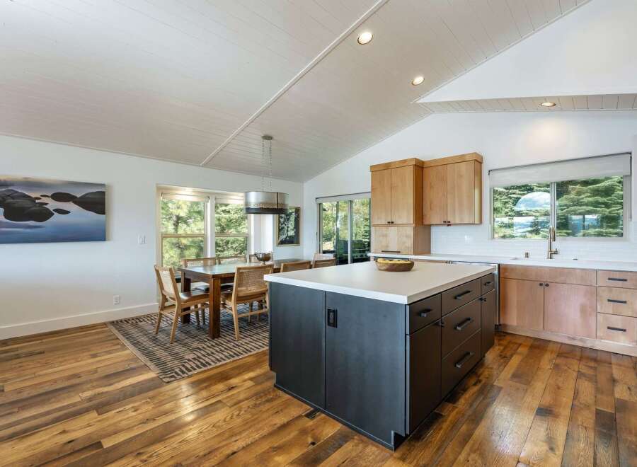 Experience modern living in this stunning kitchen and dining area, featuring a sleek dark island with ample storage and a bright, airy dining space.
