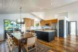 Experience modern living in this stunning kitchen and dining area, featuring sleek wood cabinetry and a spacious island perfect for entertaining.
