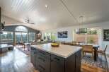 Experience breathtaking mountain views from this stunning open-concept living space, featuring a vaulted ceiling with exposed beams and a large arched window.