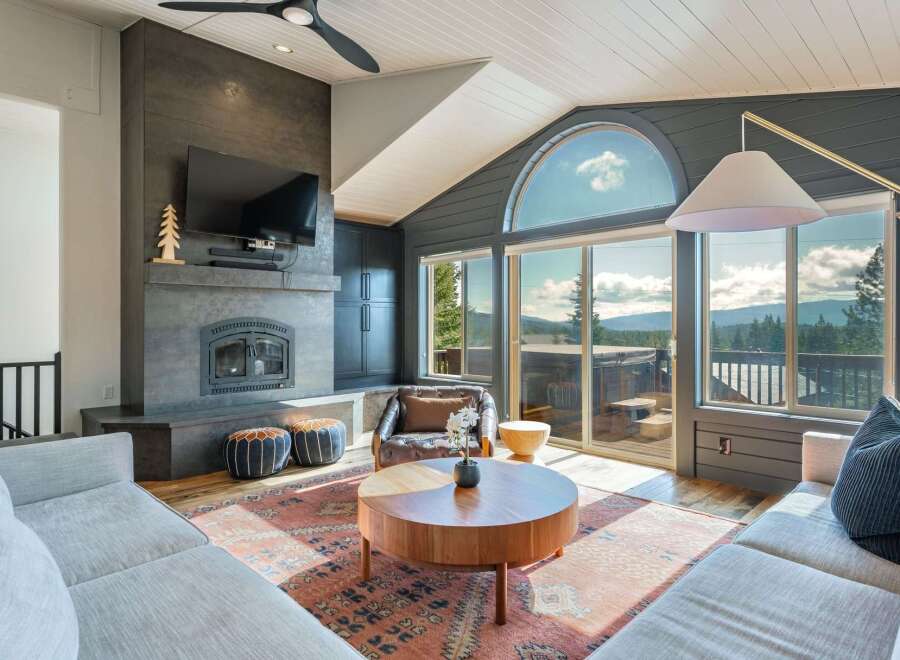 Experience breathtaking mountain views from this stunning living room, featuring a modern fireplace and expansive windows that flood the space with natural light.
