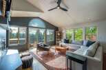 Experience breathtaking mountain views from this stunning living room, featuring a grand arched window and expansive glass doors that open to a scenic deck.