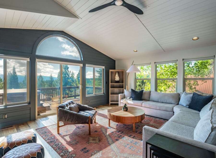Experience breathtaking mountain views from this stunning living room, featuring a grand arched window and expansive sliding glass doors that open to a scenic deck.