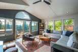 Experience breathtaking mountain views from this stunning living room, featuring a grand arched window and expansive sliding glass doors that open to a scenic deck.
