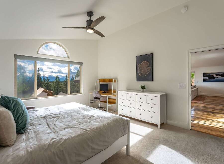 Experience breathtaking mountain views from this stunning bedroom, featuring a large window with an arched transom and a comfortable bed.