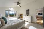 Experience breathtaking mountain views from this stunning bedroom, featuring a large window with an arched transom and a comfortable bed.