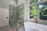 Experience luxury in this stunning bathroom featuring a spacious glass-enclosed shower with elegant tile work and a sleek rainfall showerhead.