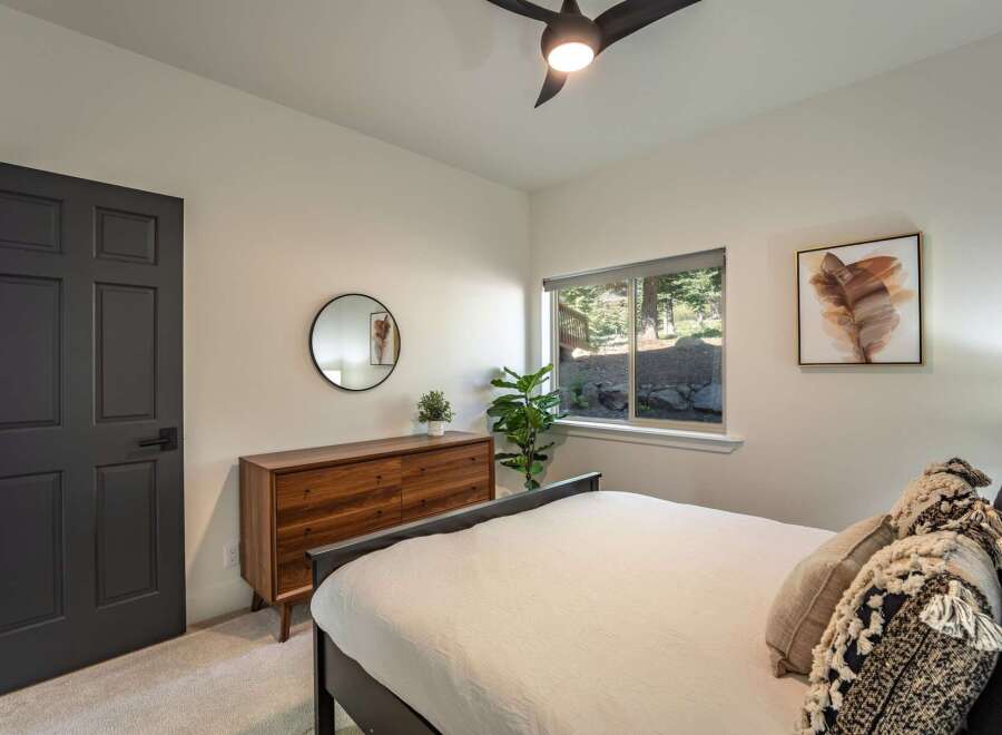 This bedroom offers a serene retreat with a stylish dark gray door and a modern wooden dresser.