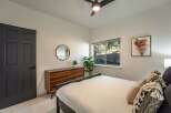 This bedroom offers a serene retreat with a stylish dark gray door and a modern wooden dresser.