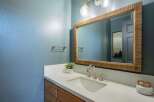 This modern bathroom features a sleek vanity with a white countertop and a undermount sink, complemented by a large, natural wood-framed mirror.