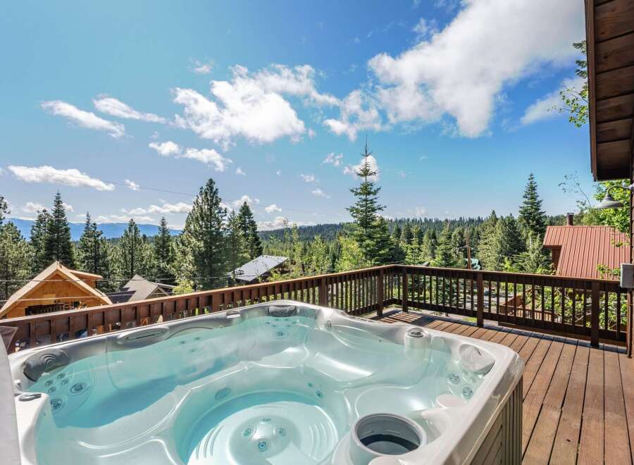 Relax and unwind in this luxurious hot tub, offering stunning panoramic views of the surrounding pine forest and distant mountains.