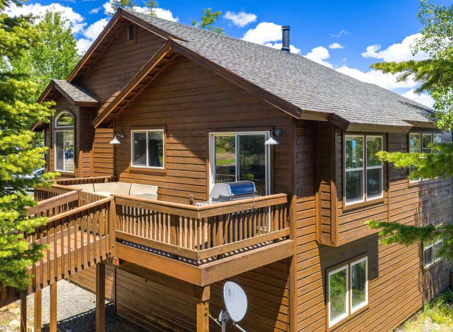 Experience mountain living in this charming wooden home, featuring a spacious wrap-around deck perfect for outdoor entertaining and enjoying the scenic views.