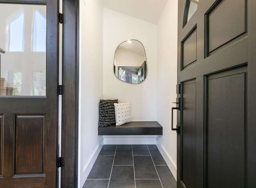 Step into this inviting entryway featuring a sleek black bench with decorative pillows, perfect for a quick seat.