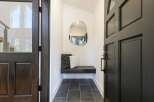 Step into this inviting entryway featuring a sleek black bench with decorative pillows, perfect for a quick seat.