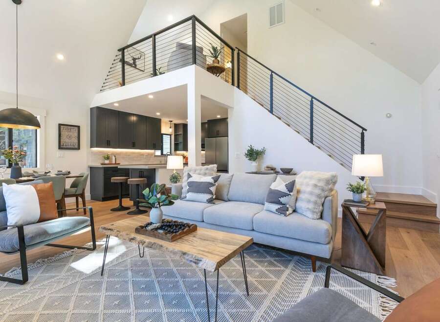 Experience modern living in this stunning open-concept home featuring a spacious living area with a vaulted ceiling and a sleek, contemporary kitchen.