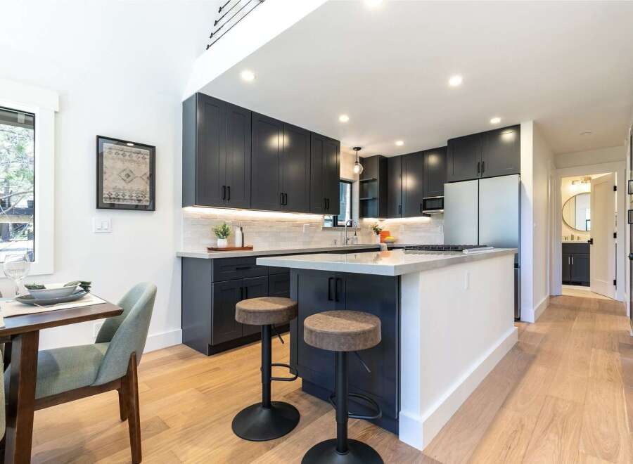 Experience modern living in this stunning kitchen featuring sleek dark cabinetry, a spacious island with bar seating, and elegant quartz countertops.