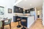 Experience modern living in this stunning kitchen featuring sleek dark cabinetry, a spacious island with bar seating, and elegant quartz countertops.