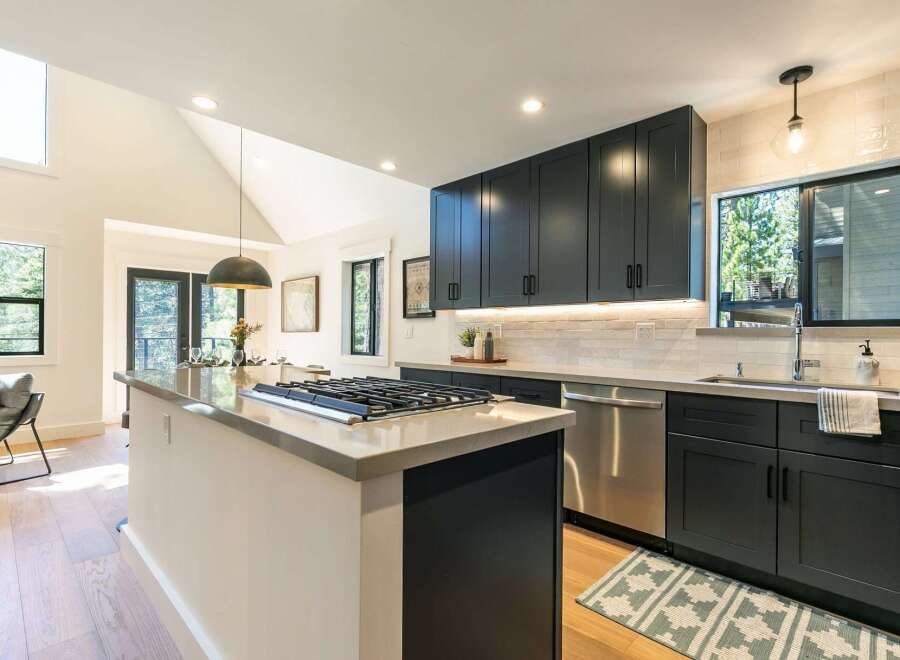 Experience modern living in this stunning kitchen featuring sleek dark cabinetry and a spacious island with a built-in gas range.