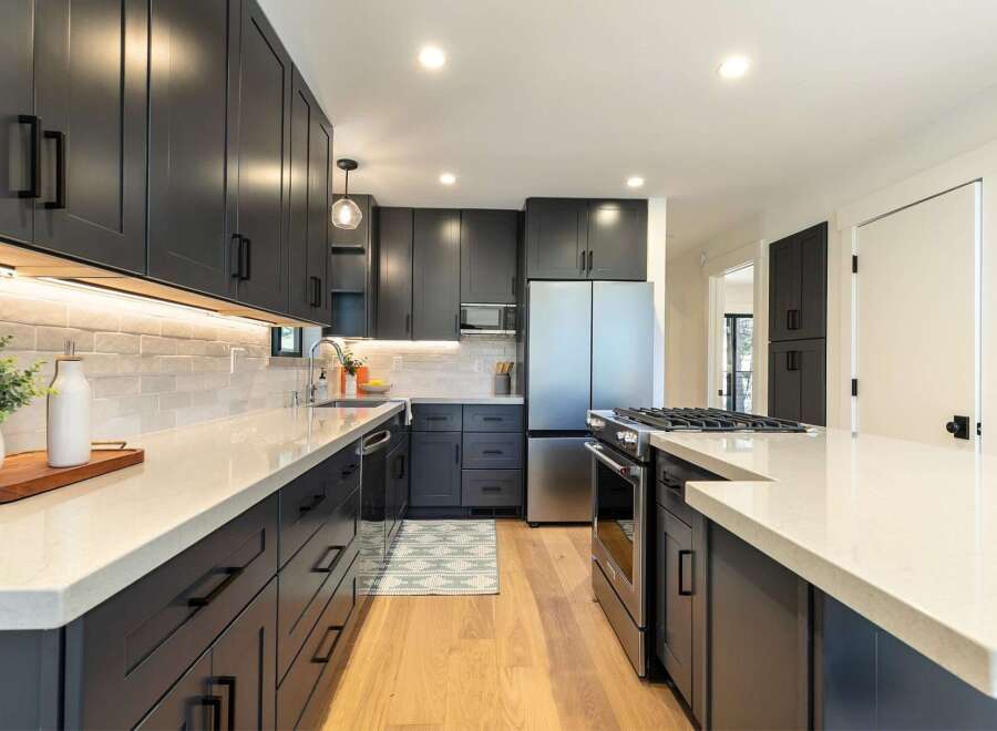 Discover this stunning modern kitchen featuring sleek, dark gray cabinetry complemented by a bright white quartz countertop.