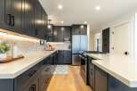 Discover this stunning modern kitchen featuring sleek, dark gray cabinetry complemented by a bright white quartz countertop.