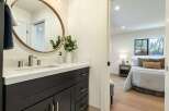 This modern bathroom features a sleek dark vanity with brushed nickel hardware and a white quartz countertop, complemented by a large oval mirror.