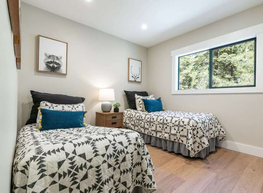 This charming bedroom features two twin beds adorned with stylish geometric-patterned quilts and plush decorative pillows.