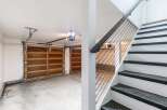 This image showcases a modern garage with two wooden garage doors and a sleek staircase with black cable railings.