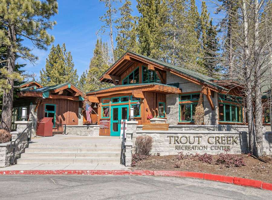 Discover the charming Trout Creek Recreation Center, a beautiful stone and wood building nestled among tall pine trees.