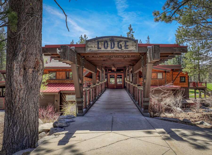 Discover this stunning lodge-style property, featuring a grand entrance with a rustic wooden walkway leading to double doors.