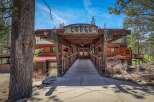 Discover this stunning lodge-style property, featuring a grand entrance with a rustic wooden walkway leading to double doors.