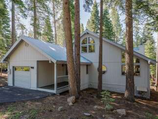 Nestled amongst tall pine trees, this charming home offers a serene mountain retreat.