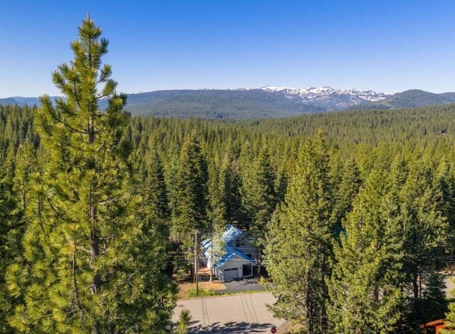 Nestled amidst a dense forest of towering pine trees, this charming home offers a serene mountain retreat.