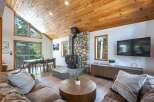 Experience cozy living in this charming cabin-style living room, featuring a striking stone fireplace with a wood-burning stove as the centerpiece.