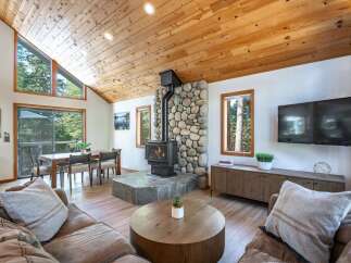 Experience cozy living in this charming cabin-style living room, featuring a striking stone fireplace with a wood-burning stove as the centerpiece.